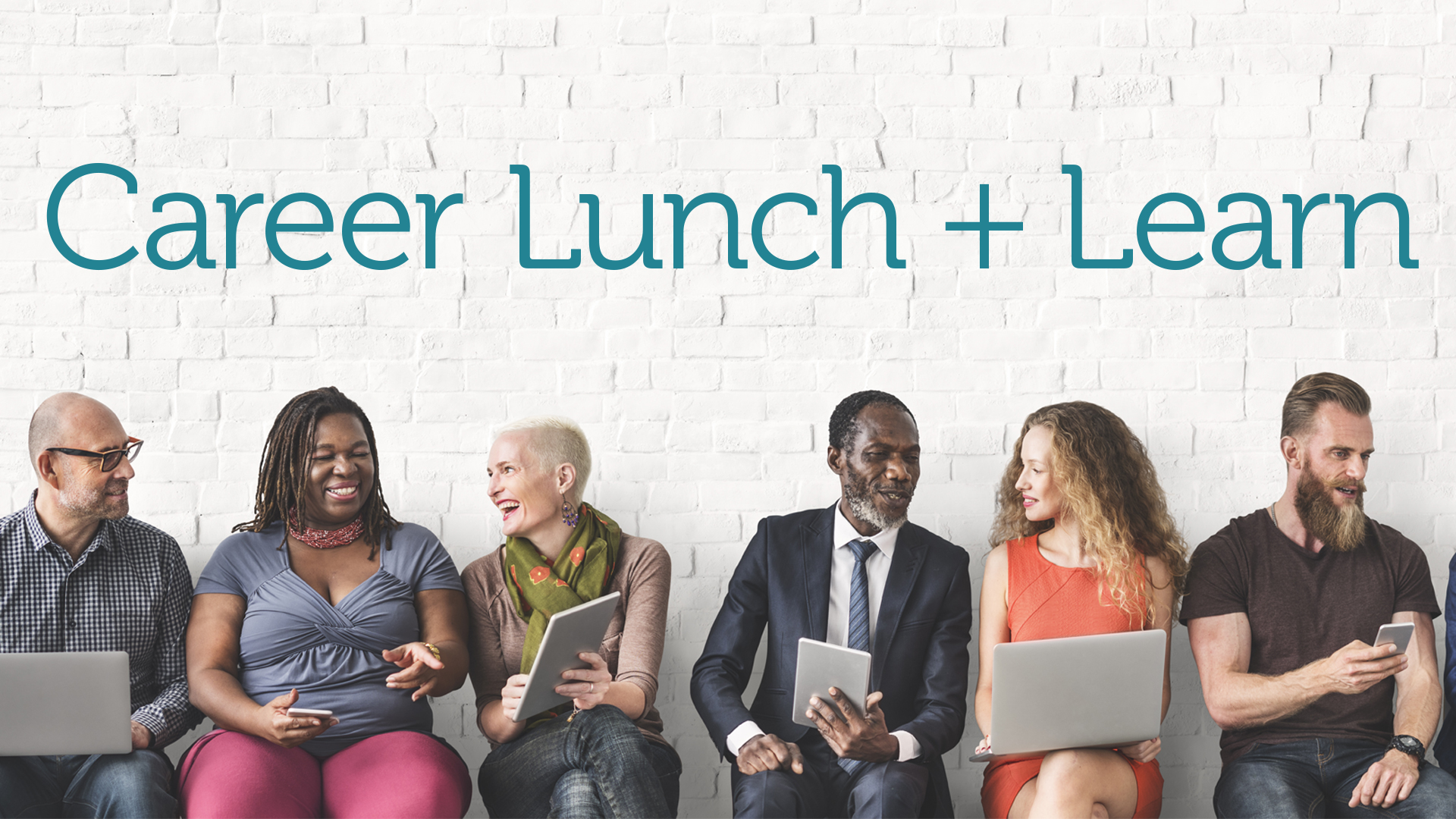 group of professional adults sitting in a row with computers and devices, smiling and talking