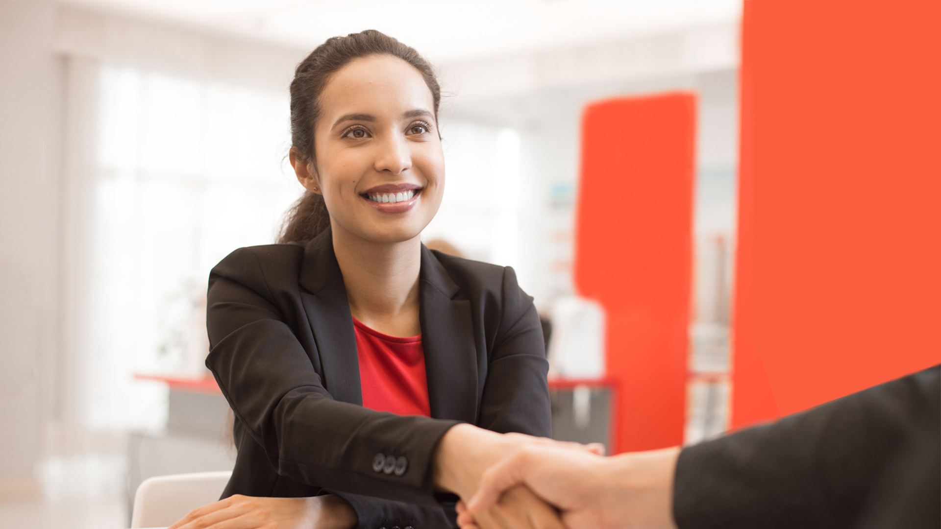 woman smiling in suit, shaking interview hand