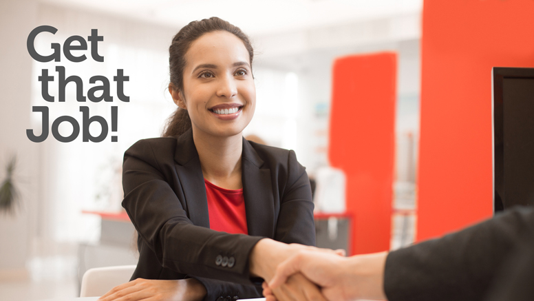 woman smiling in suit, shaking interview hand